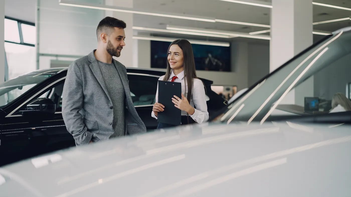 A salesperson and customer in conversation beside showroom vehicles